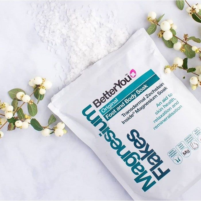 Prenade de fulgi de magneziu BetterYou albi, ambalaj de plastic pe fundal floral.