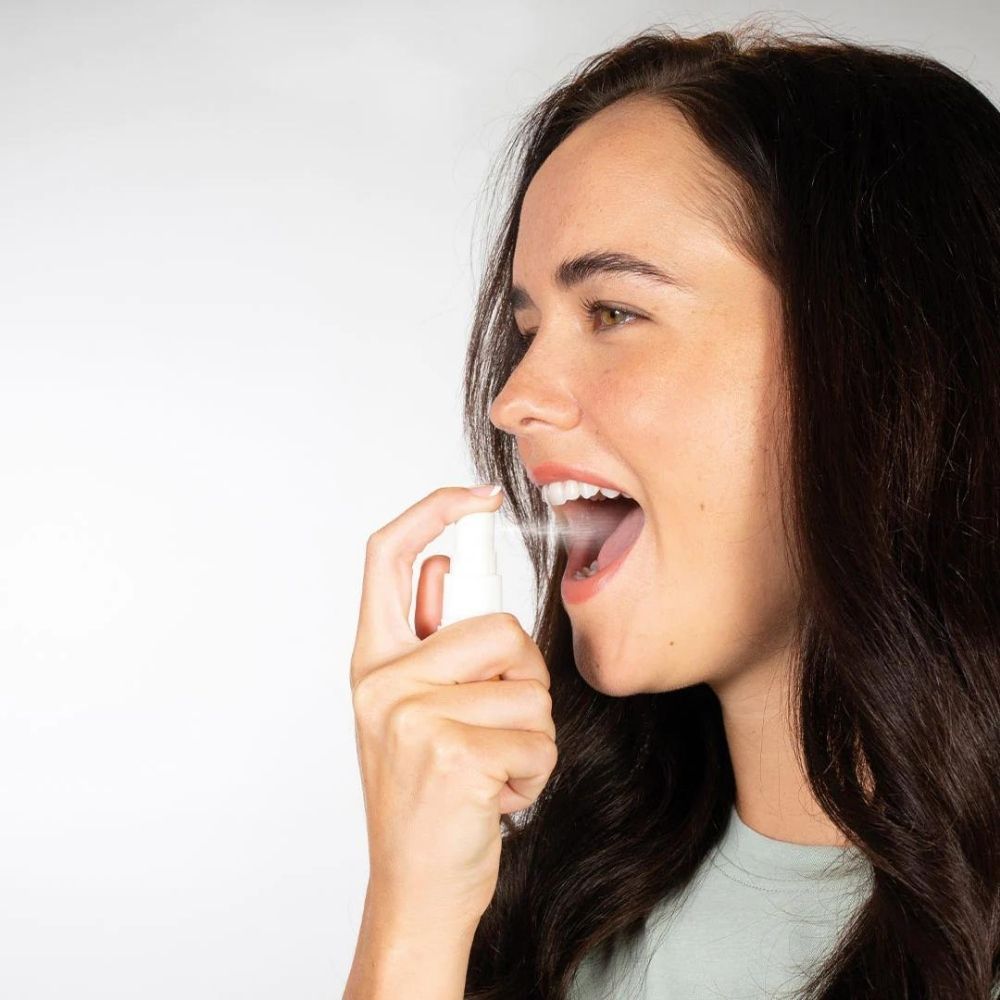 Persoană folosind spray bucal alb, aplicare orală a Multivit de 25 ml, BetterYou.