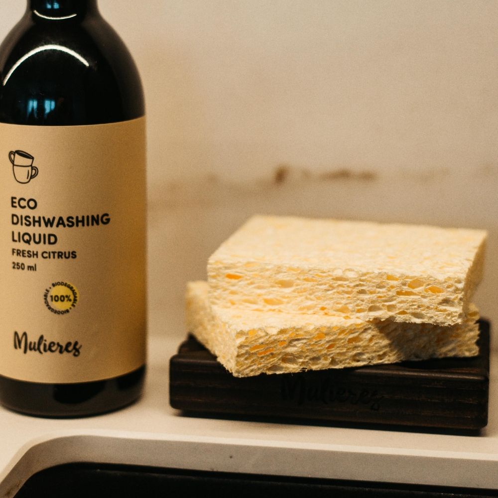 Bureți din celuloză galbenă lângă detergent lichid eco în sticlă neagră.