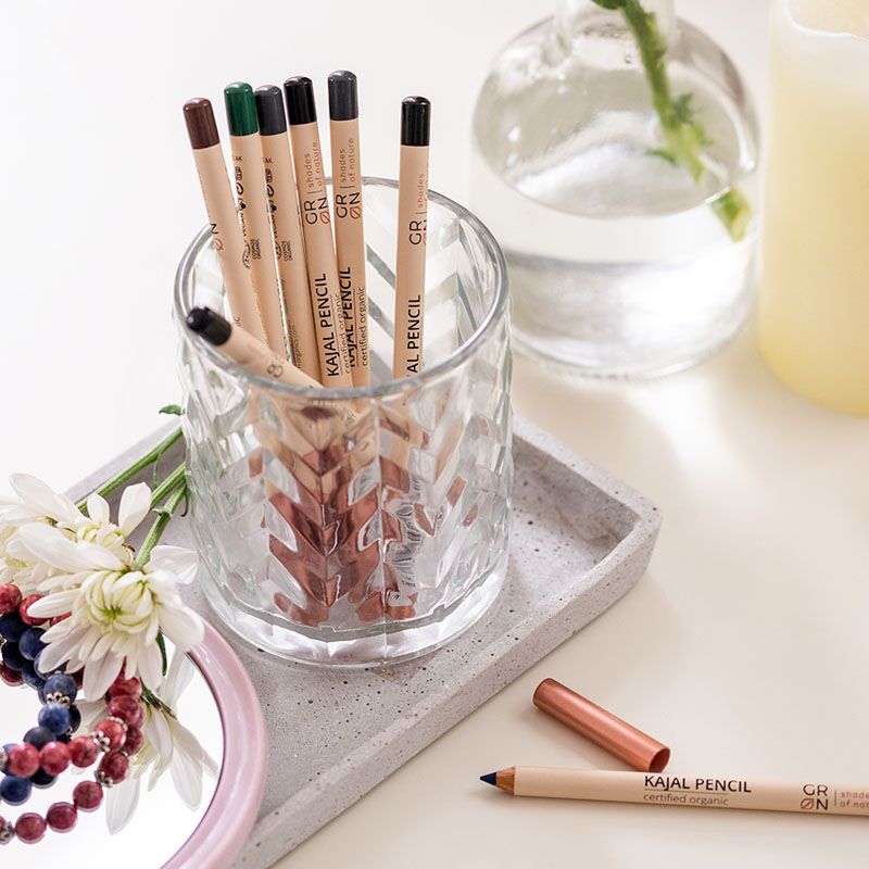 Creion Kajal Bio Organic GRN, 7 culori, suport sticlă elegant, fundal decorativ minimalistic.