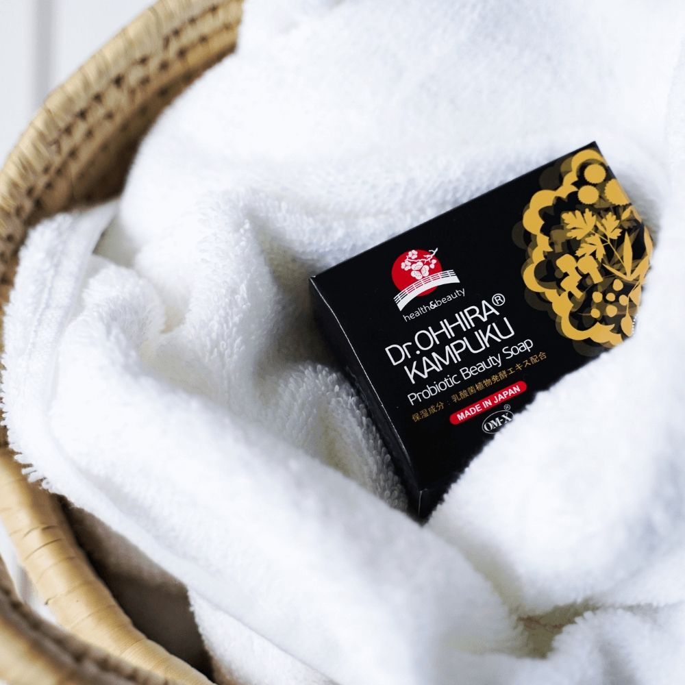 Săpun Dr.Ohhira® Kampuku, cutie neagră cu detalii aurii, așezat pe un prosop alb pufos.