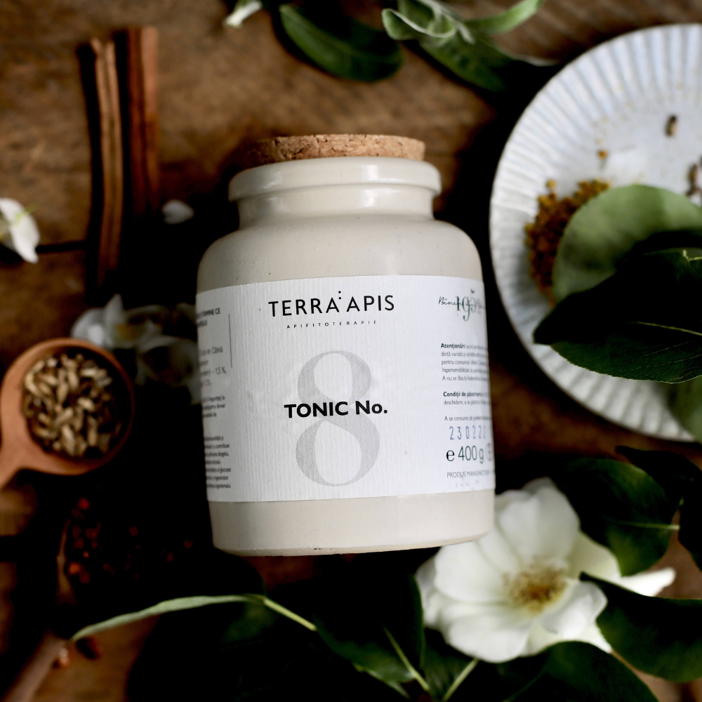 Recipient alb Terra Apis Tonic No.8, capac de plută, detalii etichetă vizibile, fundal cu plante.